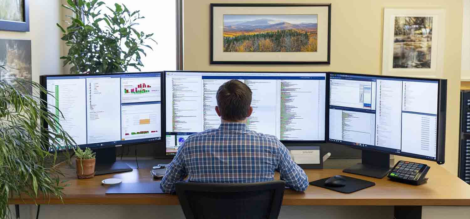 IT professional monitoring network activity on multiple screens to detect and prevent issues.