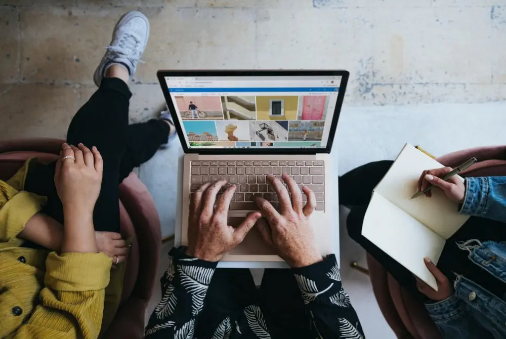 Person working on a laptop with a notebook alongside, seen from above