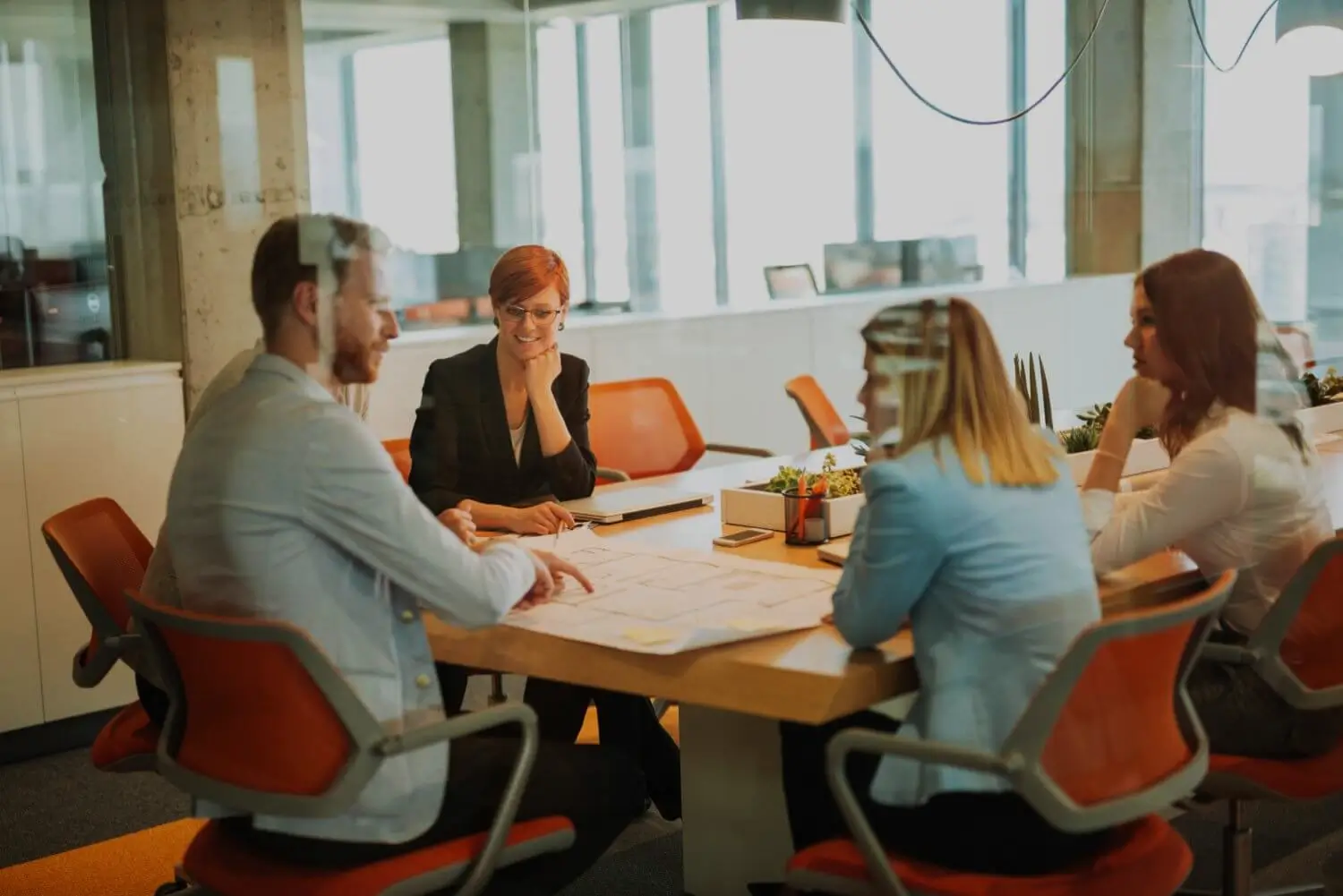 Team meeting around a boardroom table with plans spread out
