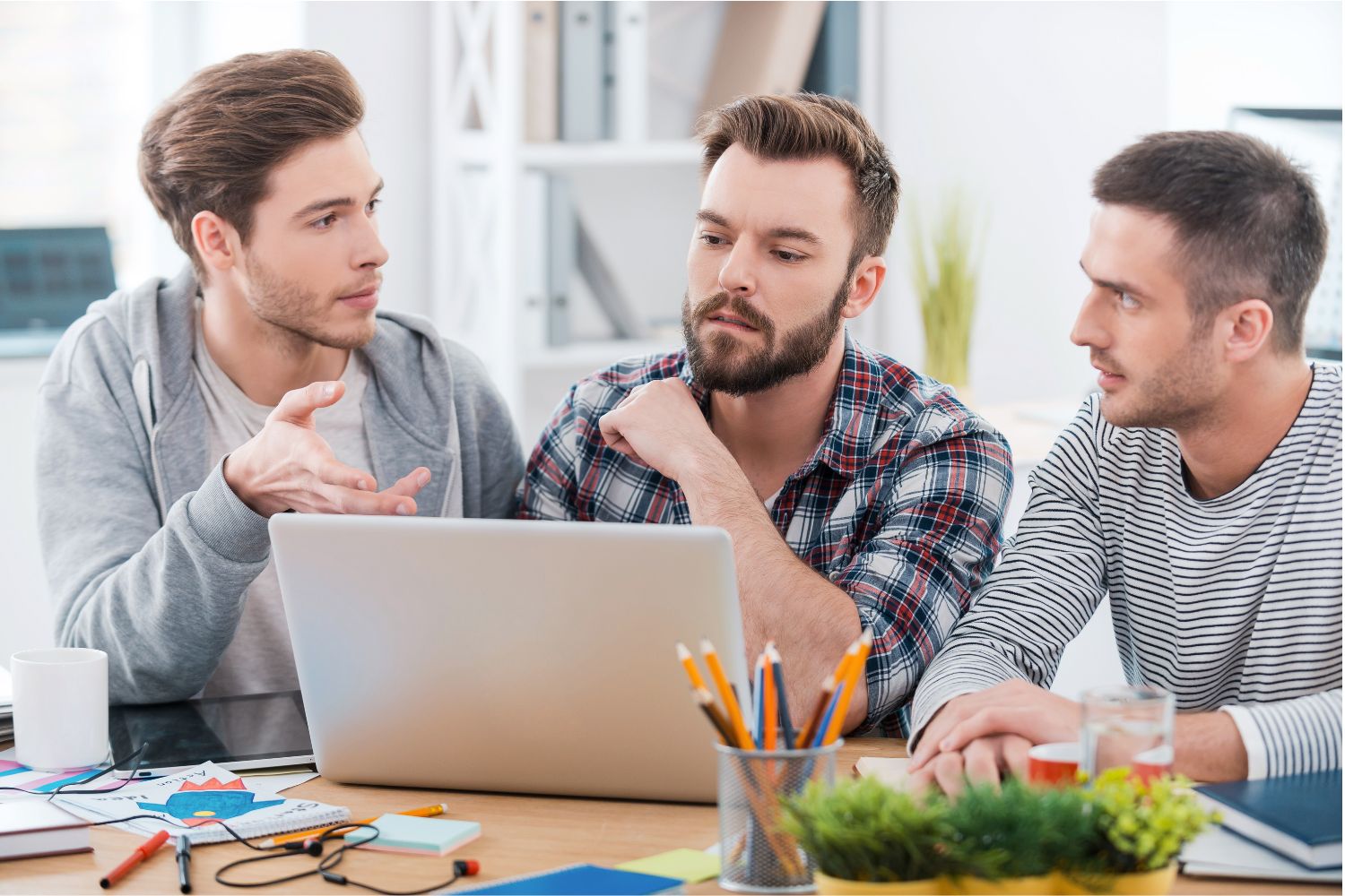 Three colleagues looking at a laptop together at a desk